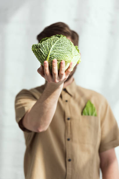 istock obscured view of man showing savoy cabbage in hand 962822210