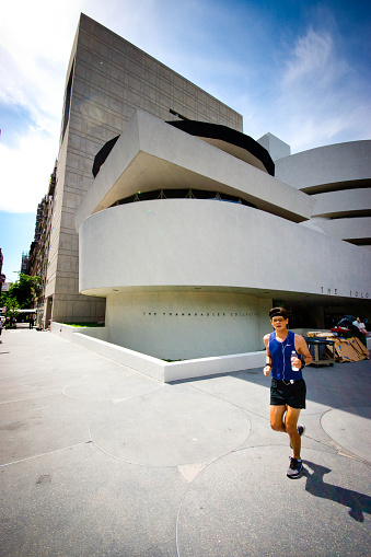 Guggenheim Museum in New York with a jogger looking at the camera. Museum was designed by Frank Lloyd Wright and building opened on October 21, 1959.