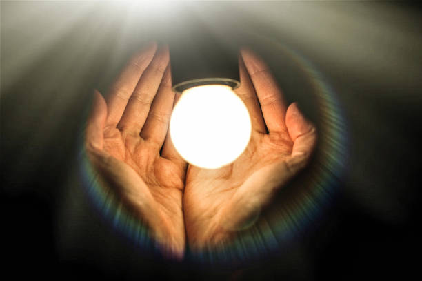 istock light bulb in humans hands on black background, energy saving and innovation concept 962827068