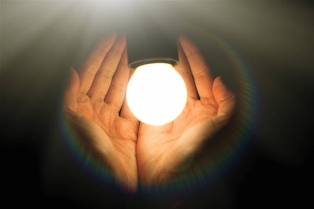 istock light bulb in humans hands on black background, energy saving and innovation concept 962827120