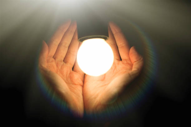 istock light bulb in humans hands on black background, energy saving and innovation concept 962827328