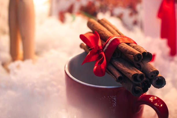 istock stylish aromatic cinnamon sticks on red cup on white background, seasonal greetings 962827564