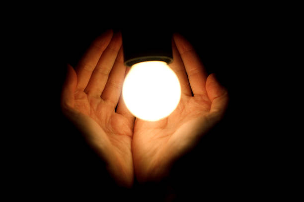 istock light bulb in humans hands on black background, energy saving and innovation concept 962827724