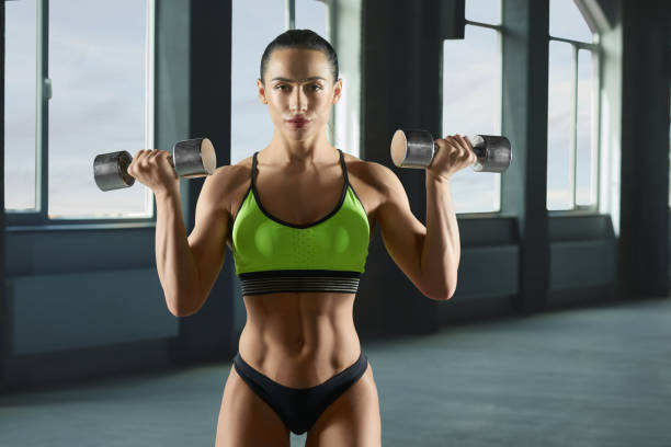 istock Woman bodybuilder lifting metallic dumbbells. 962831870
