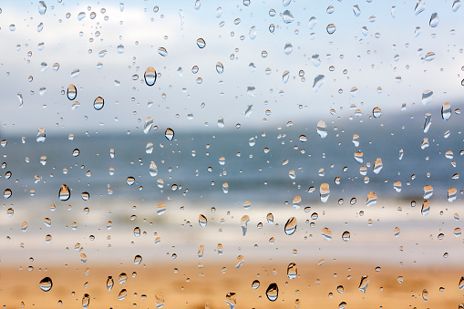 Beach, seascape through the window in a rainy day. Raindrops on the glass in the foreground, suitable for background purposes. Galicia, Spain.