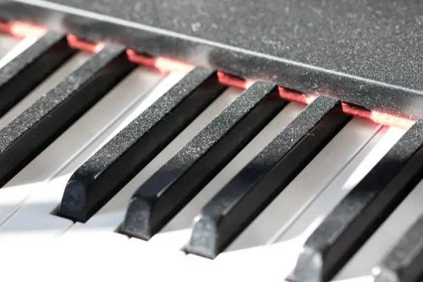 Dust on piano keys showing a lack of practice. Reluctant musician concept image showing dusty keyboard as evidence for a lack of musical instrument practise time.