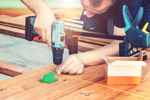 istock Construction worker screwing down wood deck with battery power screw gun or drill. 962839266