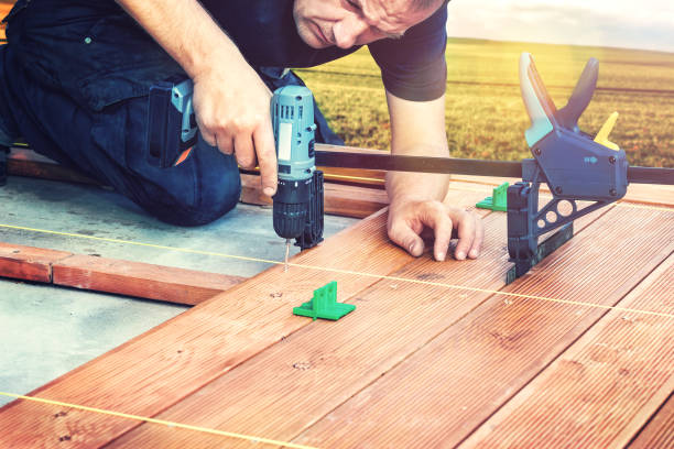 istock Construction worker screwing down wood deck with battery power screw gun or drill. 962845204