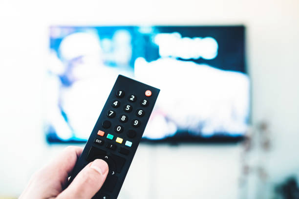 istock person using remote control against TV on white wall 962849750