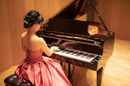 Beautiful young woman playing piano in concert