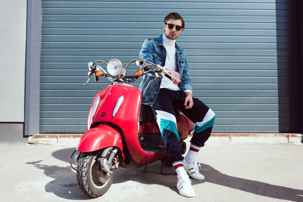 istock handsome young man in denim jacket on vintage red scooter 962858742