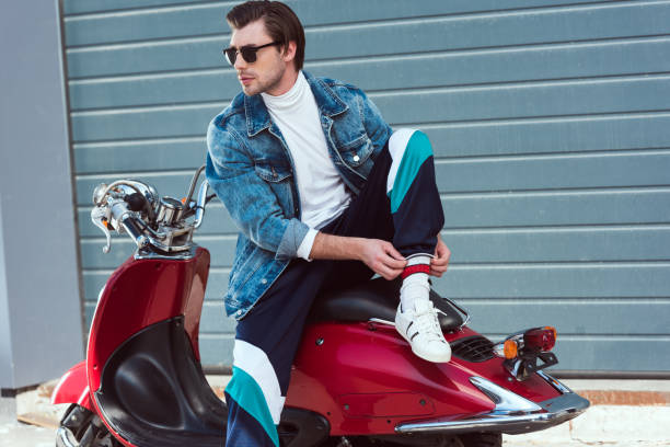 istock handsome young man in stylish clothes sitting on vintage red scooter 962860156