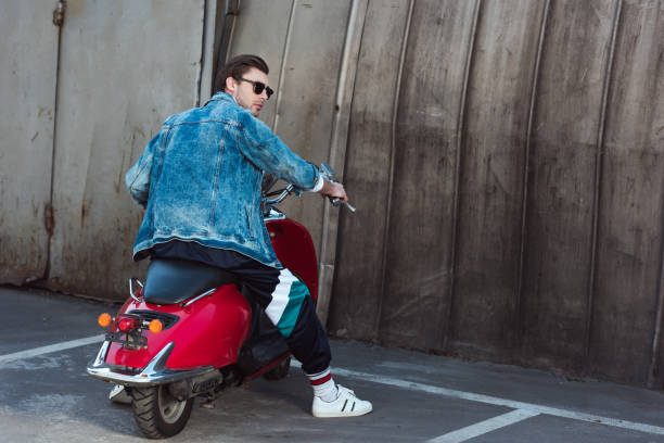 istock young man in stylish denim jacket with vintage scooter on parking 962860204