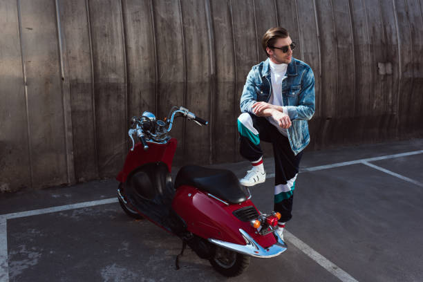 istock handsome young man in stylish denim jacket with vintage scooter on parking 962860262