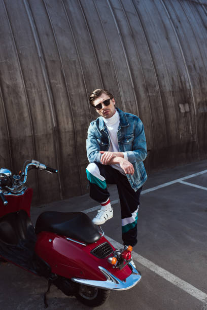 istock young man in stylish denim jacket with vintage scooter on parking 962860304