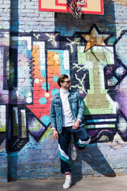 istock handsome young man in vintage clothing leaning on brick wall with graffiti 962860608