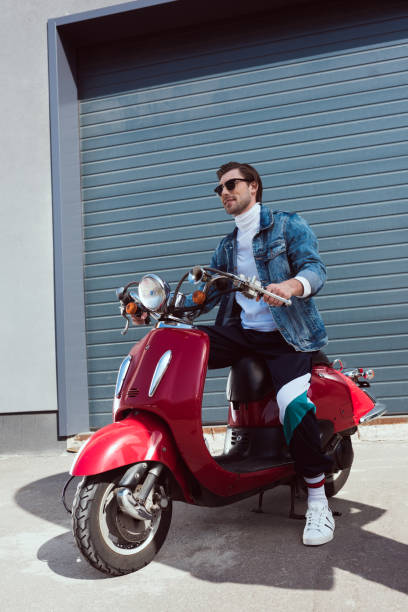 istock stylish young man in denim jacket on vintage red scooter 962866814