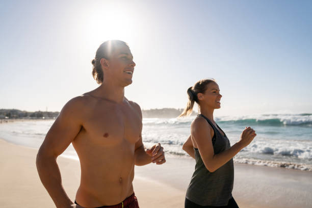 istock Athletic couple running at the beach 962869600