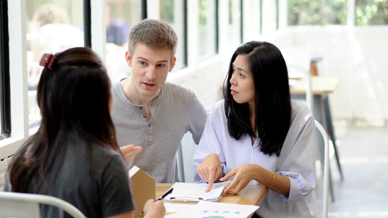 Couple having conversation discussing personal finance document loan contract, real estate purchase with sale represent.