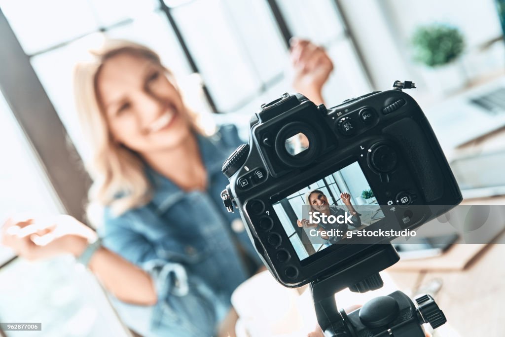 Filming. Beautiful young woman in casual wear smiling while recording video Influencer Stock Photo