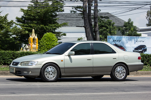 Side view of an old car parked on a locked stone paved road