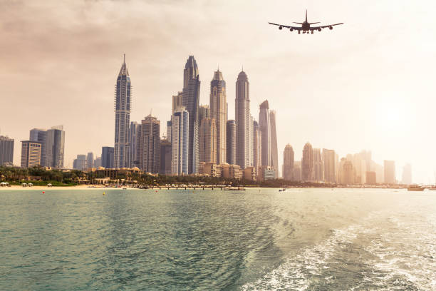 Panoramic view of Dubai from sea at sunset with an airplane on background