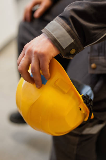 istock Worker holds yellow protective helmet in his hand 962898350