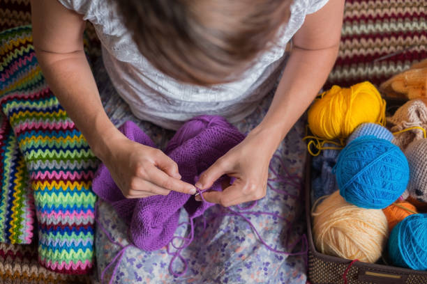 Close up senior womens hands knitting at home