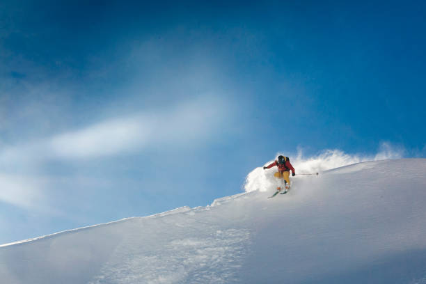 istock Young man skis off corniced ridge in powder snow 962898970