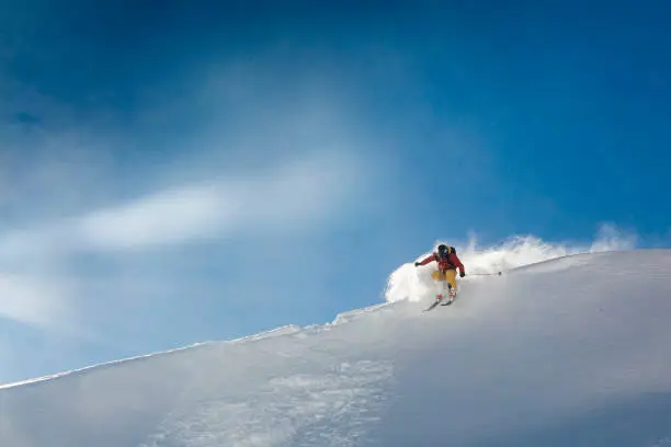 Photo of Young man skis off corniced ridge in powder snow