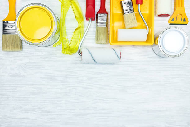 istock various paintbrushes, paint can, protective glasses, rollers, paint tray, putty knife on grey wooden surface 962903408