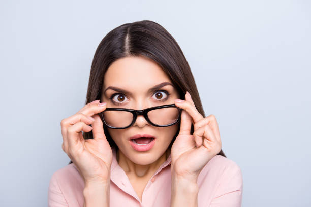 portrait de femme impressionnée, choquée, en colère, stressée tenant des oeillets de lunettes sur son visage avec les deux mains regardant des spectacles avec la bouche grande ouverte, isolé sur fond gris - mouth open women displeased anger photos et images de collection