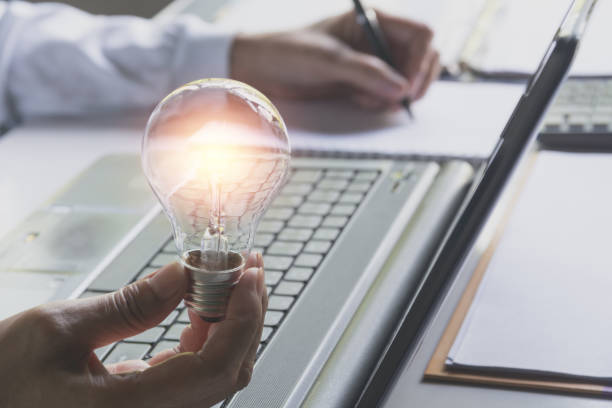 istock Hand of male holding a light bulb and using a laptop for accounting and creative concept. 962911288