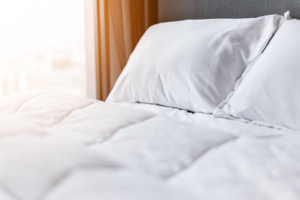 ベッド メイド-きれいな白い枕とベッドのシーツで美容室アップ。クローズ アップ。日光の下でのレンズの才能。 - bedroom hotel hotel room inn ストックフォトと画像