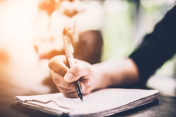 istock woman student writing something on white blank paper with blur image background 962911640