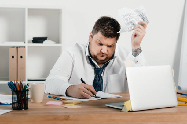 istock overweight businessman working with documents and laptop in office 962914302