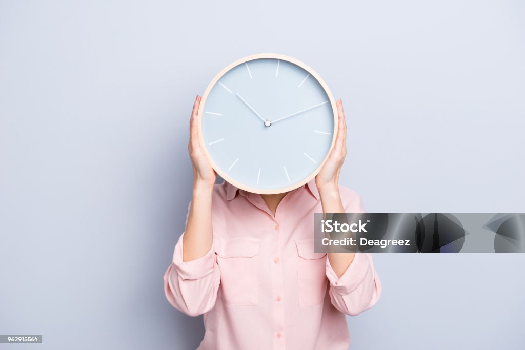 It's 10:10 o'clock. Portrait of charming pretty positive cheerful woman closing covering head face with round clock isolated on grey background Time Stock Photo