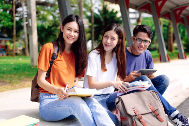Three young Asian people studying together at outdoors. Education and Technology concept. Lifestyles and Happy life in classroom theme. People and Leisure theme. Back to school