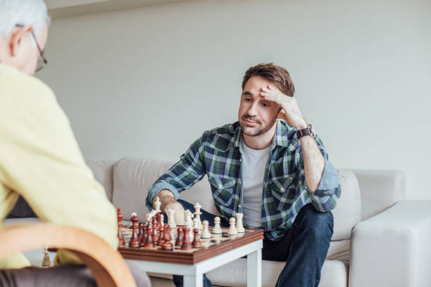 istock Serious young man holding hand on his head while playing chess 962925002