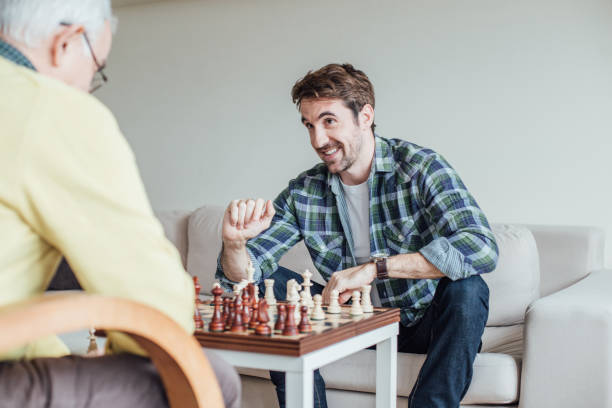 istock Happy young man smiling and playing chess with a parent 962925036