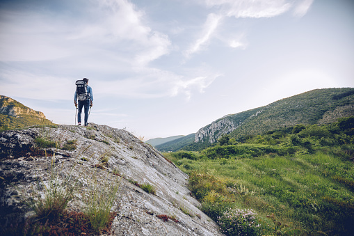 One man, walking high on mountain alone, enjoying the view, rear view.