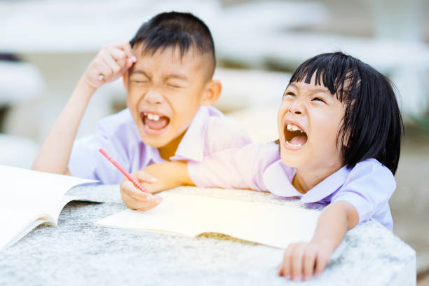 Happy kids thinking together homework on desk in uniform school