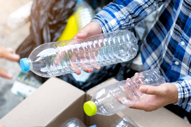 istock Hand holding recyclable plastic bottle in garbage bin with sunset light 962930492