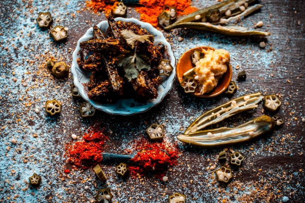 istock Popular Indian Brunch dish i.e Barali bindi/crispy okra or bharli bindi a dish made from raw ladies finger and other vegetables with spices by frying it.On a wooden surface in dark Gothic colors. 962934668