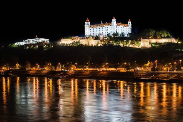 Bratislava at night, with the city lights reflected in the Danube river. On the top hill stands the Bratislava Castle construction built in the 9th century. Bratislava, Slovakia May 23, 2018: Bratislava at night, with the city lights reflected in the Danube river. On the top hill stands the Bratislava Castle construction built in the 9th century. bratislava castle bratislava castle fort stock pictures, royalty-free photos & images