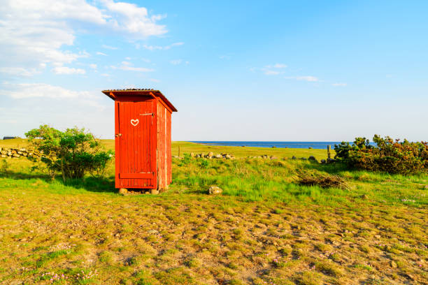 Red outhouse Lovely little red outhouse on a coastal meadow on a sunny day. Outhouse stock pictures, royalty-free photos & images