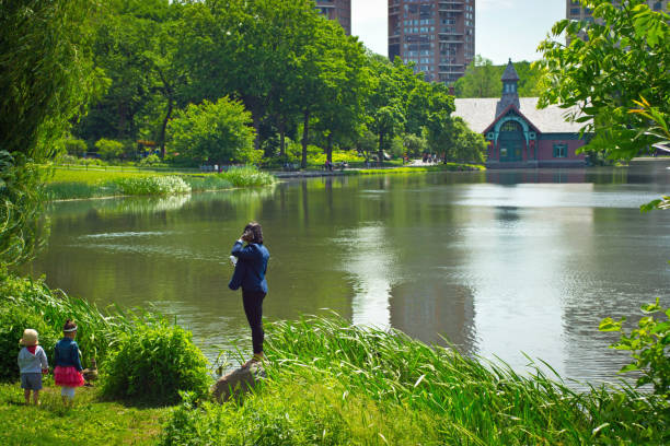 A young family at the  lake in Central Park, Manhattan looking across towards the boat house.