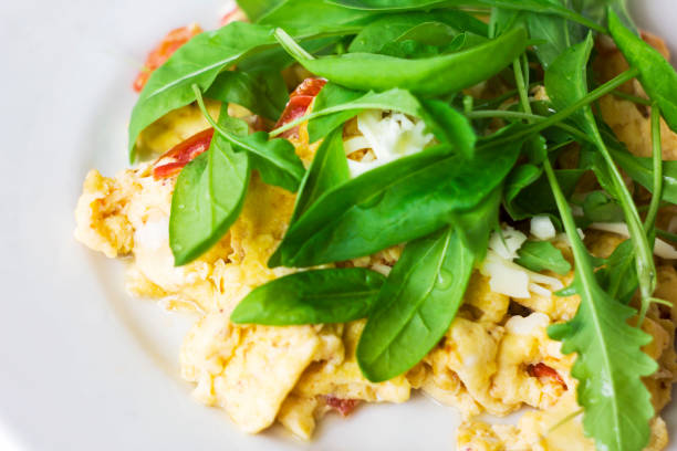 istock Egg omelet with tomato and fresh arugula spinach in white plate 962948546
