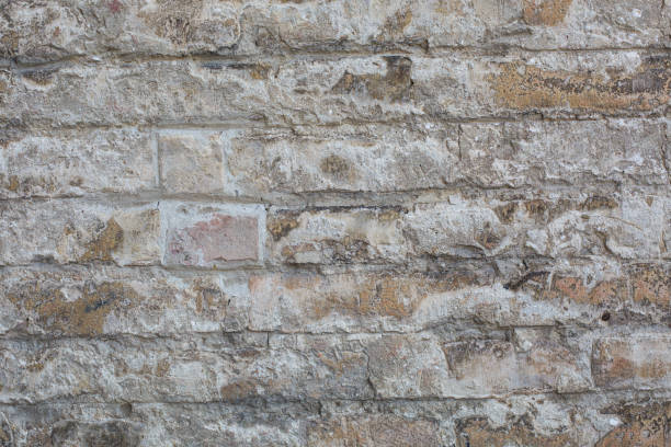 istock Old wall made of big stones and broken bricks. Vintage rough blocks surface background 962963412