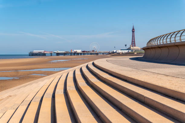 Seafront leading to the Blackpool Tower by the beach in Blackpool, Lancashire\n+ signs and logos removed. People in distance too small to be recognisable